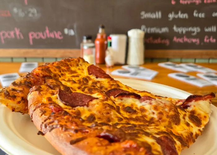 Person holding pizza slice on a plate